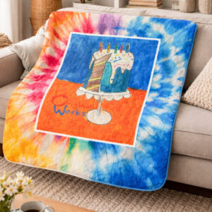 Quilted blanket with cake artowrk and tie dye background on a couch