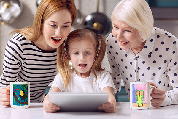 Smiling at laptop with original works mugs